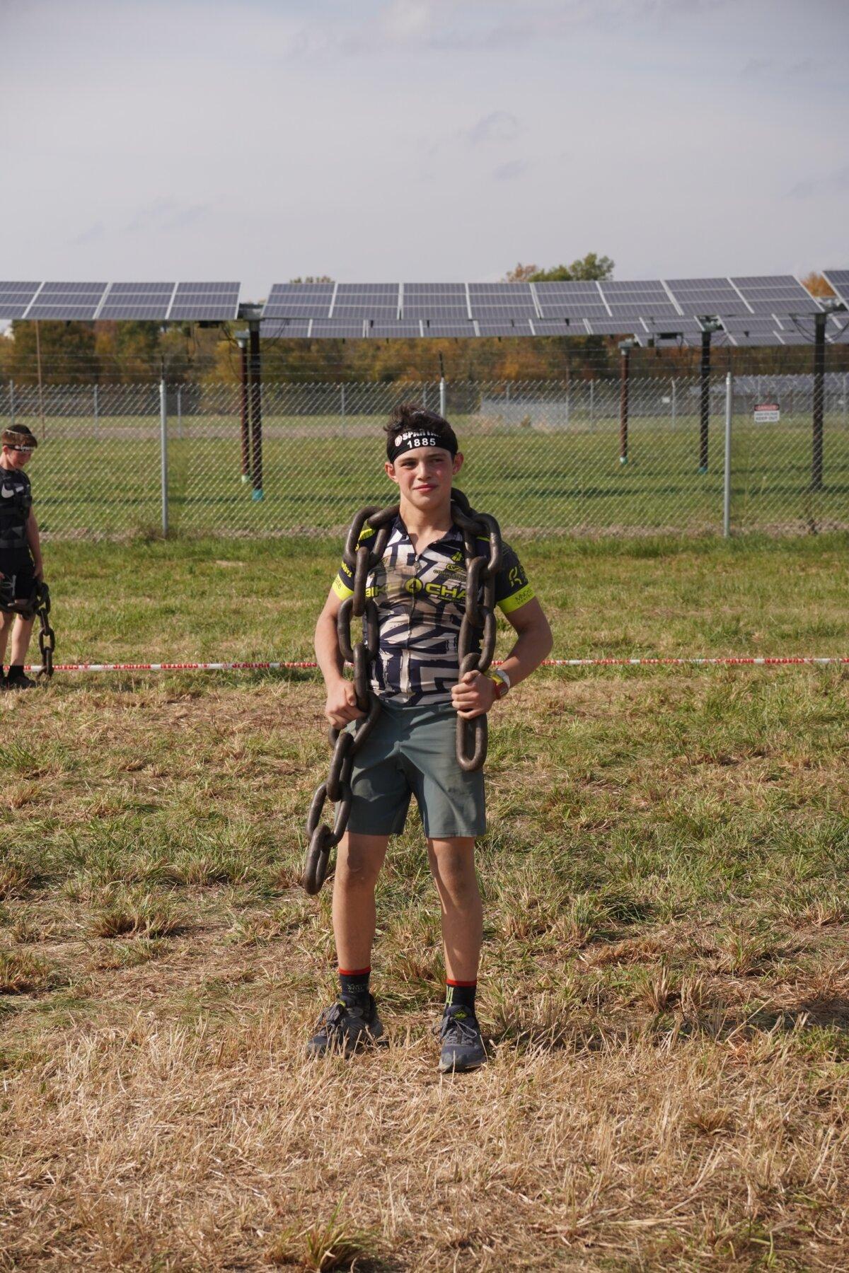 Runner carries a heavy chain at the 2025 Tri-State New York Spartan Event Weekend in the Town of New Hampton, N.Y., on Oct. 19, 2025. (Oliver Mantyk/The Epoch Times)