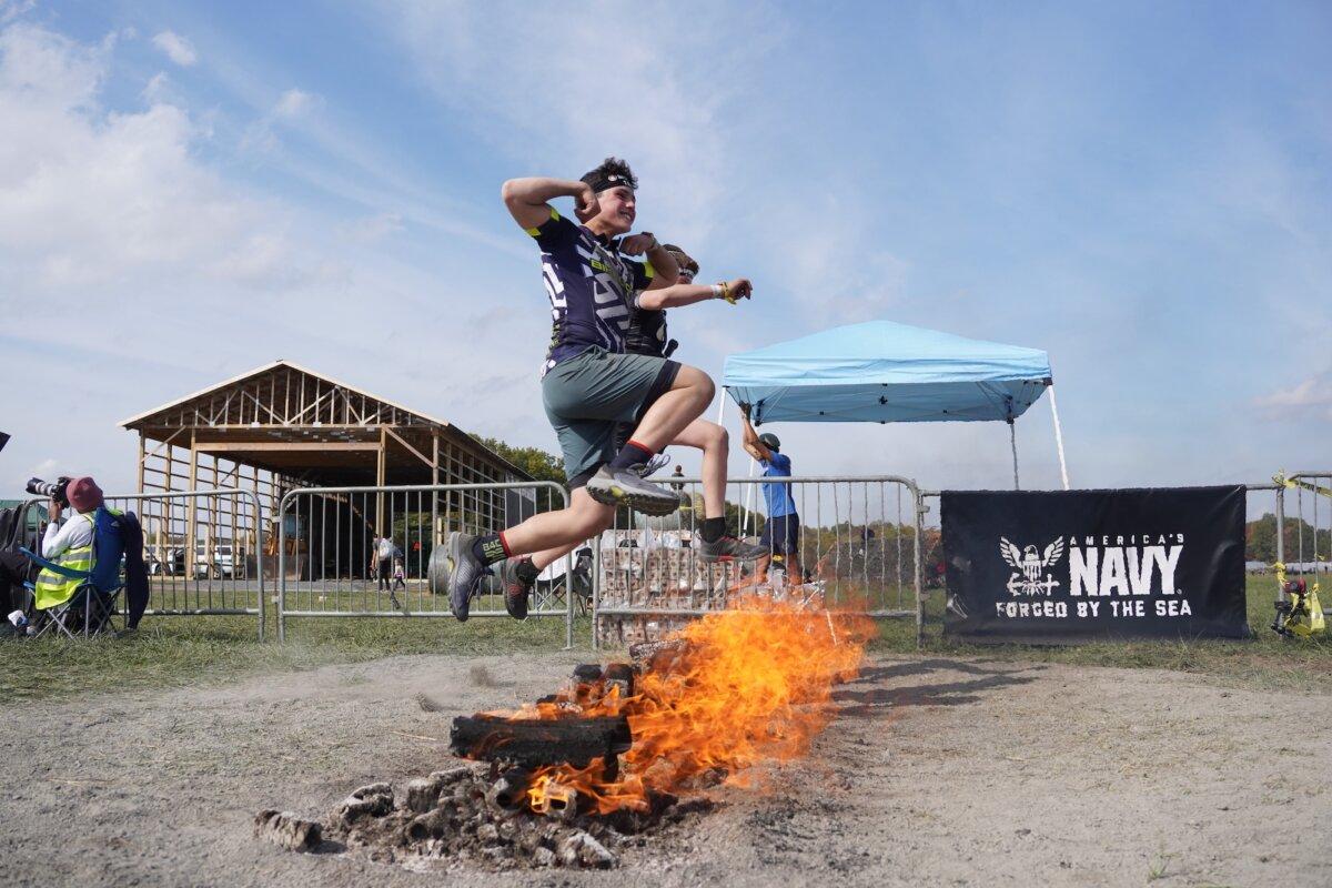 Runners jump fire at the 2025 Tri-State New York Spartan Event Weekend in the Town of New Hampton, N.Y., on Oct. 19, 2025. (Oliver Mantyk/The Epoch Times)