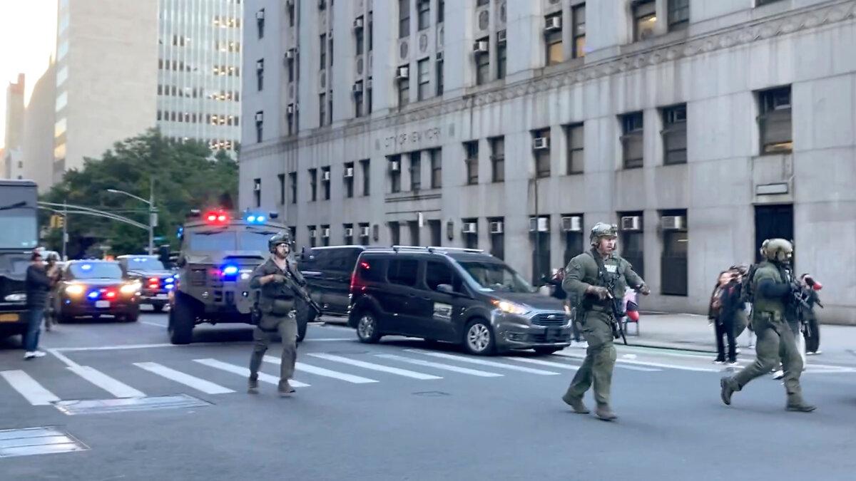 Federal agents walk down Lafayette Street as demonstrators follow along after an immigration sweep on Canal Street through Chinatown in New York on Oct. 21, 2025. (AP Photo/Jake Offenhartz)