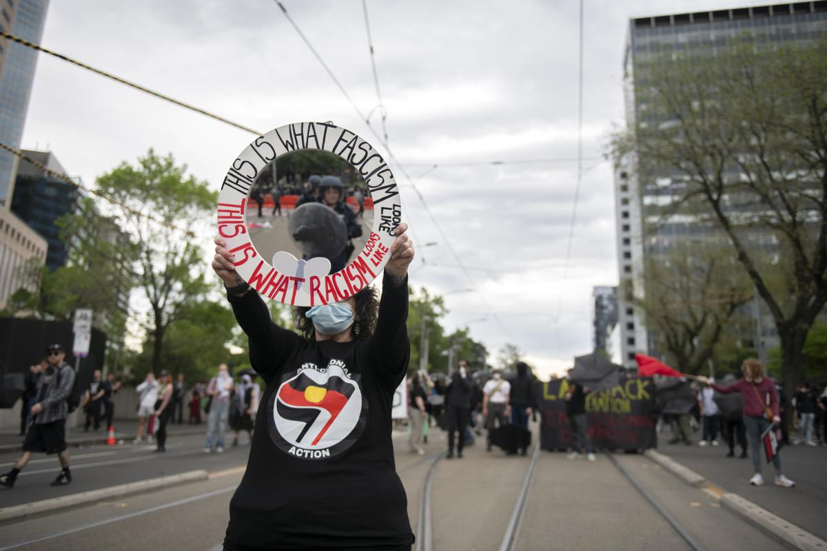 A protestor wearing a shirt emblazoned with an Antifa-inspired logo that says,