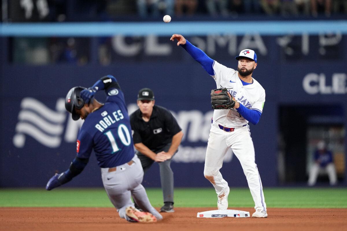 Isiah Kiner-Falefa of the Toronto Blue Jays throws to first base after forcing out Victor Robles of the Seattle Mariners at second base to complete a double play during the seventh inning in the American League Championship Series at the Rogers Centre in Toronto, Canada, on Oct. 20, 2025. (Mark Blinch/Getty Images)