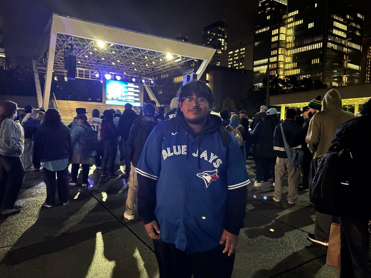 Justin Subaskaran watches the Toronto Blue Jays' first game in the World Series against the LA Dodgers at a viewing party at Nathan Phillips Square in Toronto on Oct. 24, 2025. (Olivia Gomm/The Epoch Times)