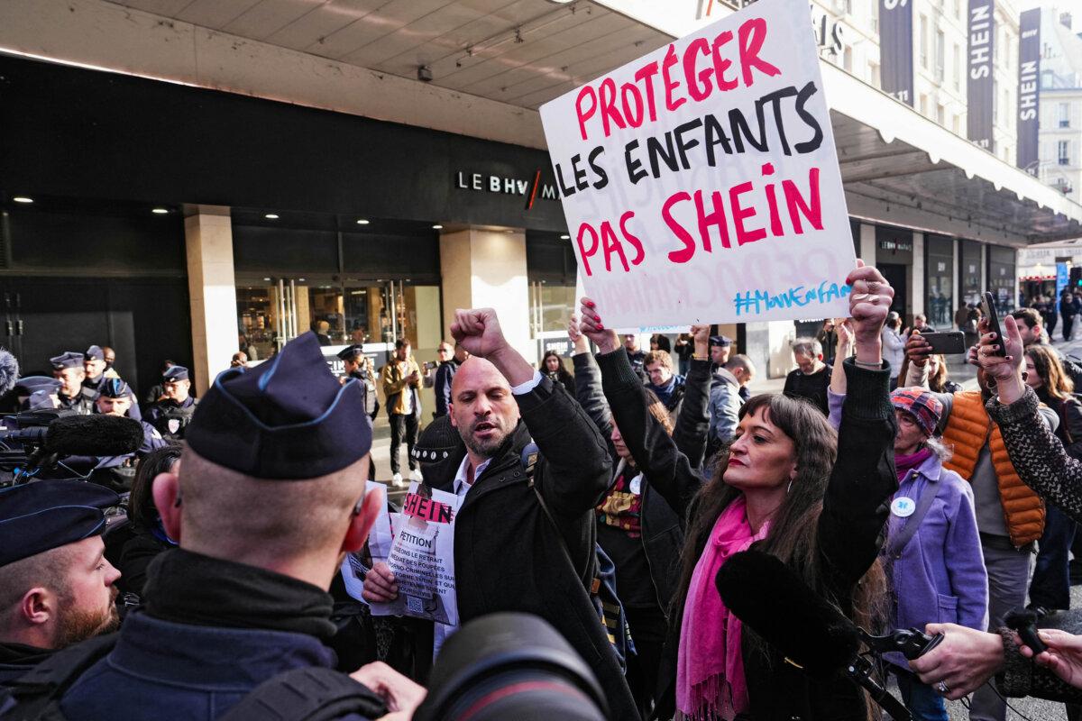 Arnaud Gallais (C), president of Mouv'Enfants, a movement fighting against all forms of violence against children, gestures next to Suzanne Frugier (R), general secretary of Mouv'Enfants, holding a placard which reads as "Protect children. Not Shein," at the Bazar de l'Hotel de Ville (BHV) department store in Paris on Nov. 5, 2025. (Dimitar Dilkoff/AFP via Getty Images)
