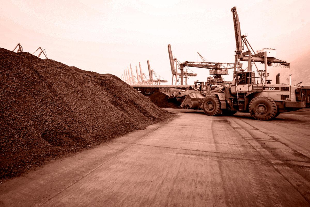 A man drives a front loader to shift soil containing rare earth minerals for export to Japan at a port in Lianyungang, Jiangsu Province, China, on Sept. 5, 2010. (Edited by The Epoch Times, STR/AFP via Getty Images)