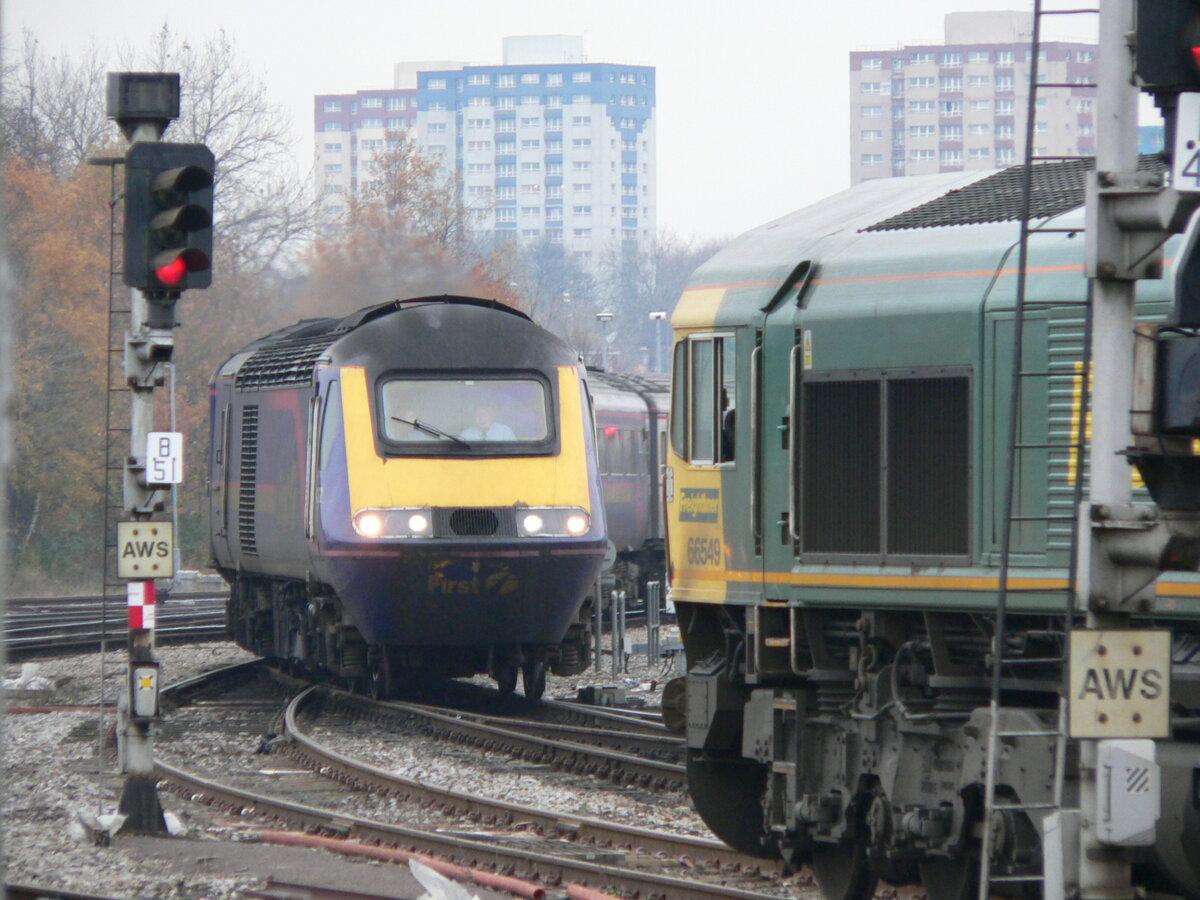 A Class 66 locomotive (R) is waiting at a red signal while a First Great Western (now Great Western Railway) passenger train (L) crosses its path at a junction. (<a href="https://en.wikipedia.org/wiki/User:Thryduulf">Thryduulf</a>/<a href="https://creativecommons.org/licenses/by-sa/4.0">CC BY-SA 4.0</a>)