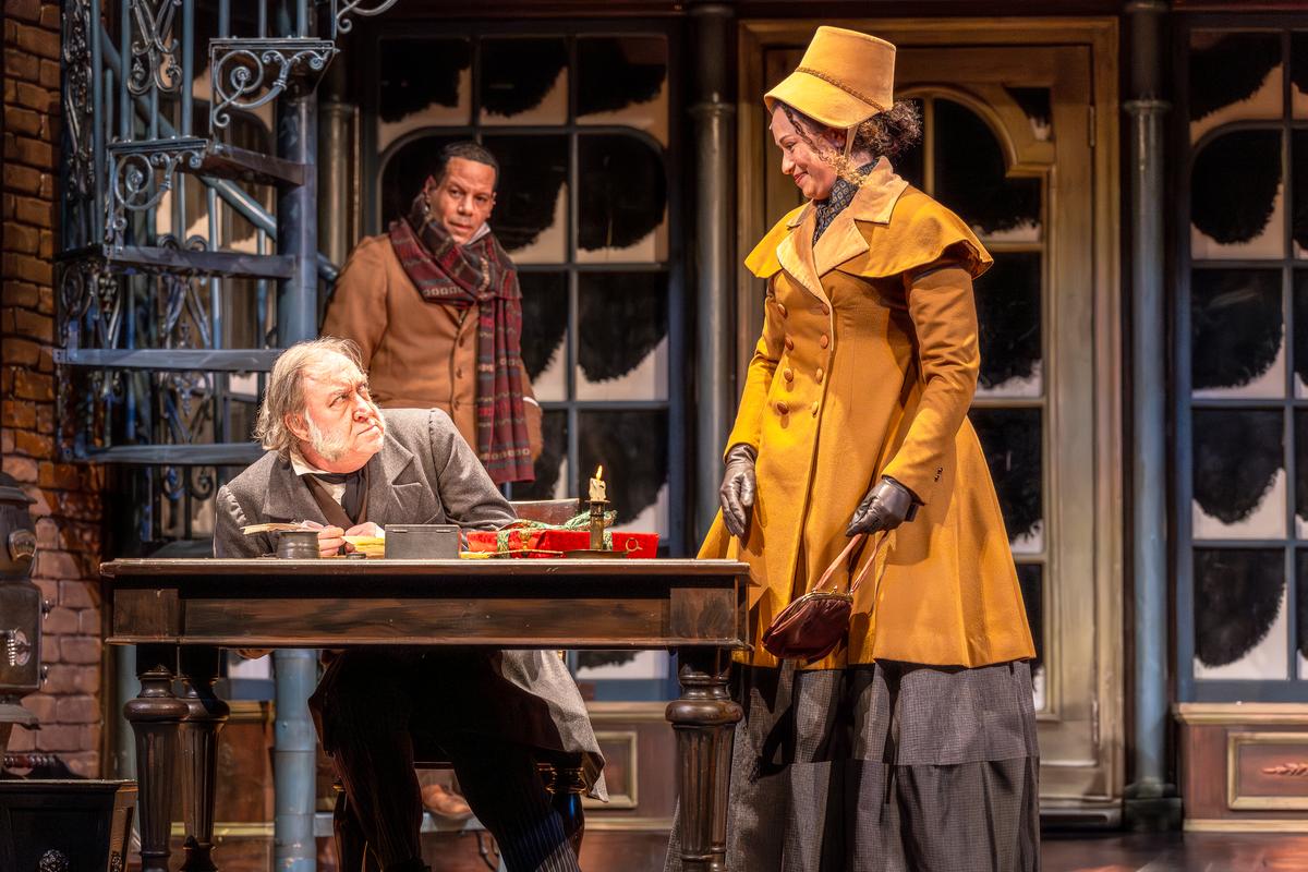 (L–R) Ebenezer Scrooge (Christopher Donahue), Bob Cratchit (Jon Hudson Odom), and Frida (Amira Danan), in "A Christmas Carol." (Brett Beiner)