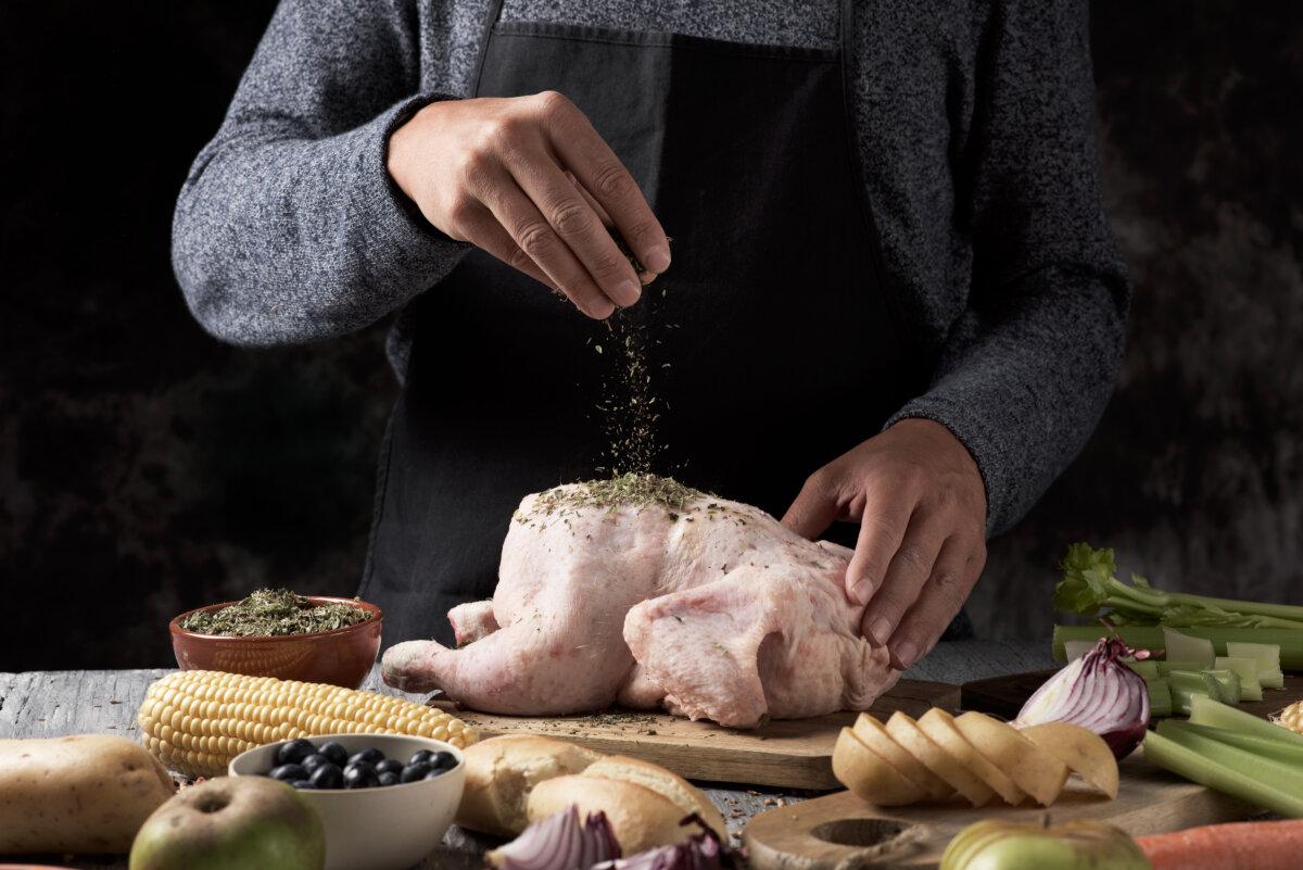 Young caucasian man preparing a turkey placed on a table full of ingredients to stuff it. (Nito100/Getty Images)