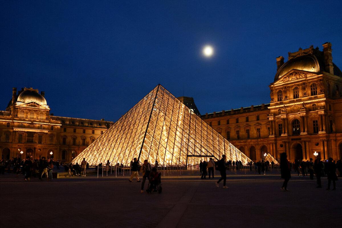 People walk near the glass Pyramid of the Louvre museum after it was announced that French police had arrested more suspects linked to the theft of treasures from the museum's Galerie d'Apollon (Apollo gallery), in Paris, France, on Oct. 30, 2025. (Abdul Saboor/Reuters)