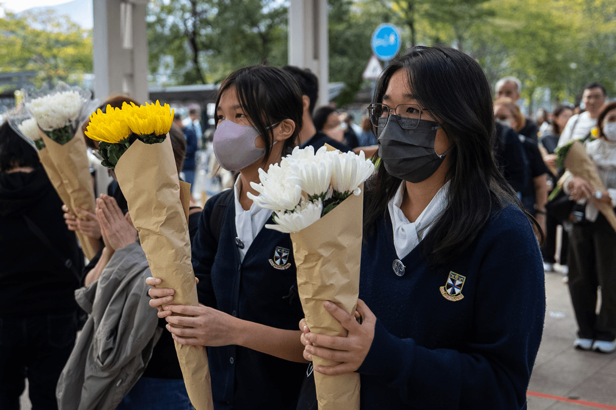 People offer flowers for the victims near the site of a deadly Wednesday fire at Wang Fuk Court, a residential estate in the Tai Po district, New Territories, Hong Kong on Dec. 1, 2025. (Chan Long Hei/AP Photo/)