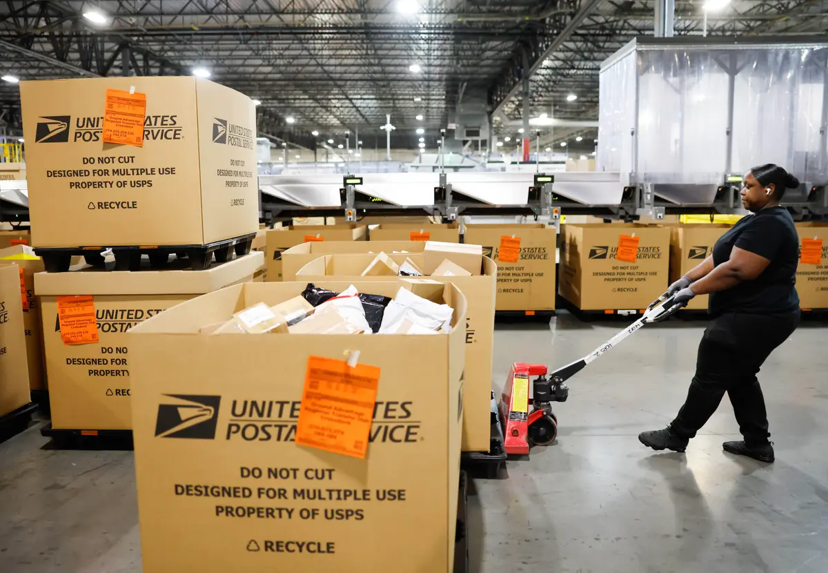 A U.S. Postal Service employee transports parcels for distribution during the start of the holiday mail rush, following Black Friday and Cyber Monday, inside the Los Angeles Mail Processing & Distribution Center in Los Angeles on Dec. 2, 2025. (Mario Tama/Getty Images)