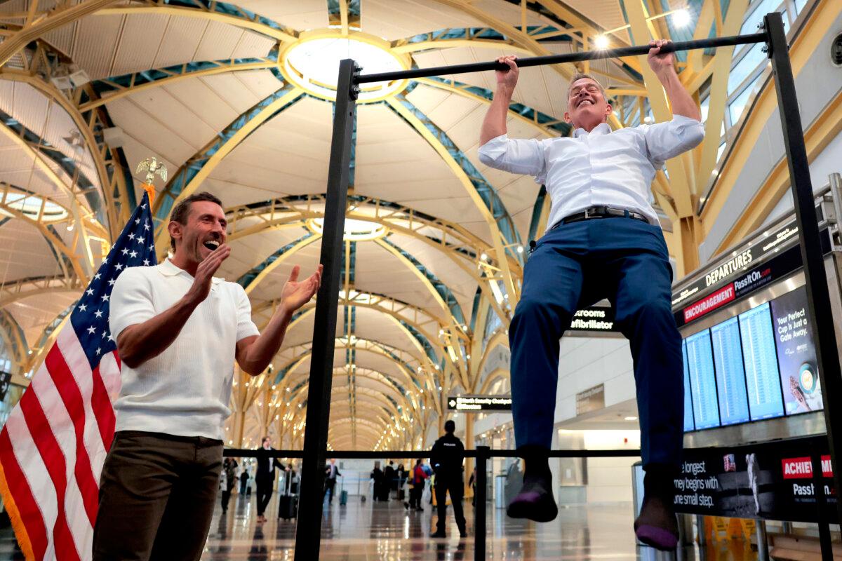 Trump Admin Aims to Create Family-Friendly Airports With Healthier Foods, Exercise Areas | USNN World News Influencer Dr. Paul Saladino watches Transportation Secretary Sean P. Duffy do pull-ups after a press conference discussing the launch of the "Make Travel Family Friendly Again" campaign at Ronald Reagan Washington National Airport in Arlington, Va., on Dec. 8, 2025. (Heather Diehl/Getty Images)