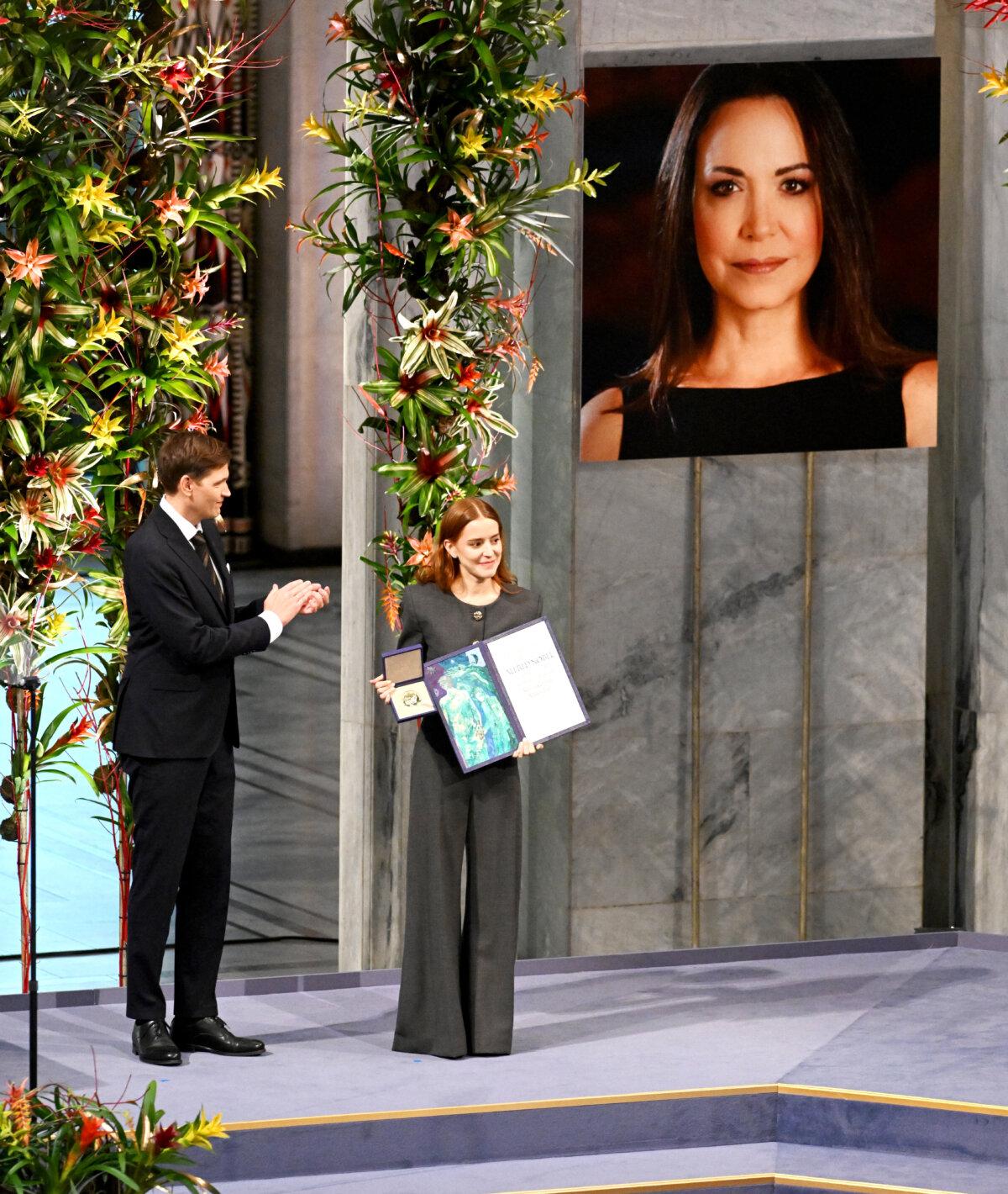 Machado Plans Venezuela Return, Says Trump’s Pressure Has Weakened Maduro Regime | USNN World News Venezuelan politician María Corina Machado's daughter Ana Corina Sosa Machado accepts the Nobel Peace Prize on her behalf at The Nobel Peace Prize Ceremony at Oslo City Hall in Oslo, Norway, on Dec. 10, 2025. (Rune Hellestad/Getty Images)