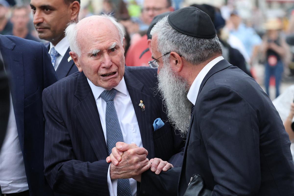 Former Australian Prime Minister John Howard (L) shakes hands with a rabbi at Bondi Beach memorial in Sydney, Australia, on Dec. 21, 2025. (David Gray/AFP via Getty Images)