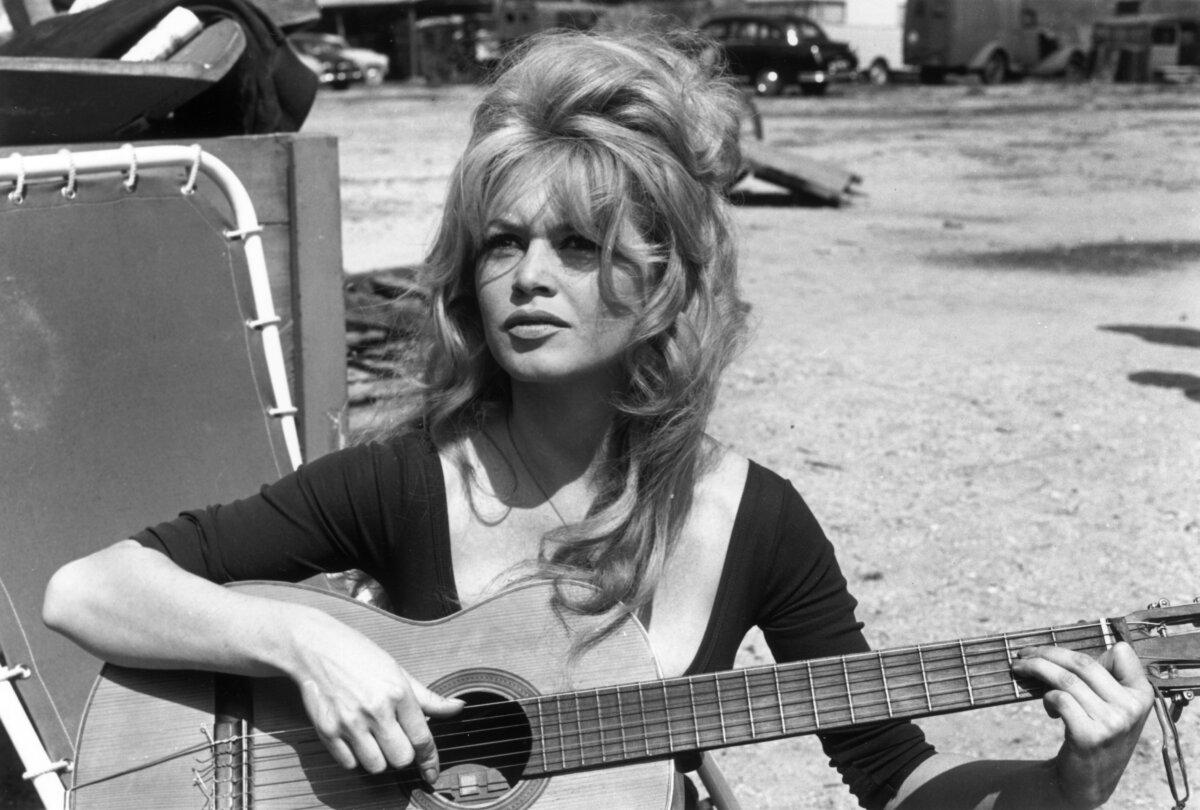 French actress Brigitte Bardot plays guitar in an empty lot, circa 1960. (Hulton Archive/Getty Images)