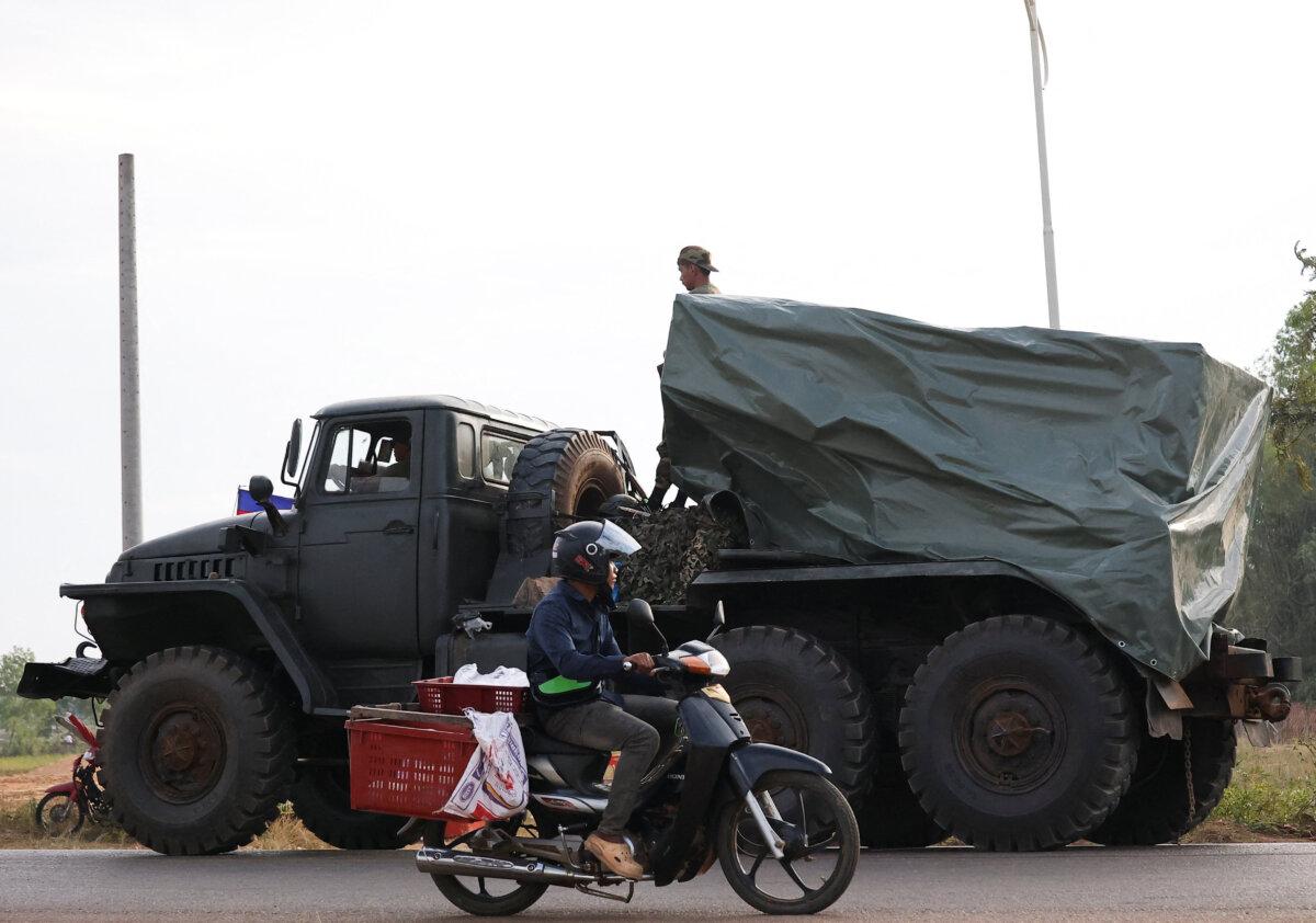 A man drives past a military vehicle heading toward the border, amid deadly clashes between Thailand and Cambodia along a disputed border area, in Srei Snam, Cambodia, on Dec. 10, 2025. (Kim Hong-Ji/Reuters)