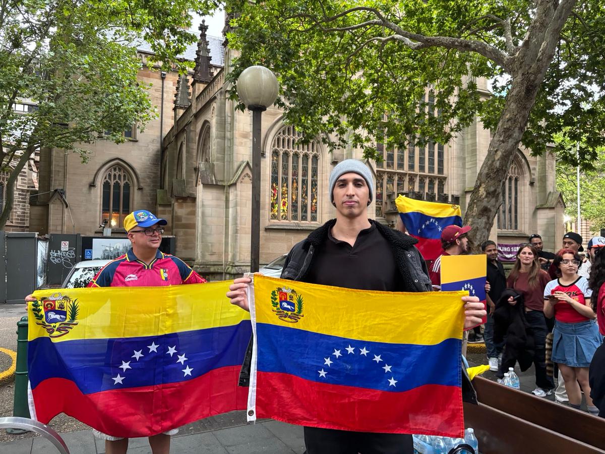 Venezulean Isaias Vego holds up his home country's flag at a celebration held in Sydney's CBD, Australia on Jan. 4, 2026. (Hailey Do/The Epoch Times)