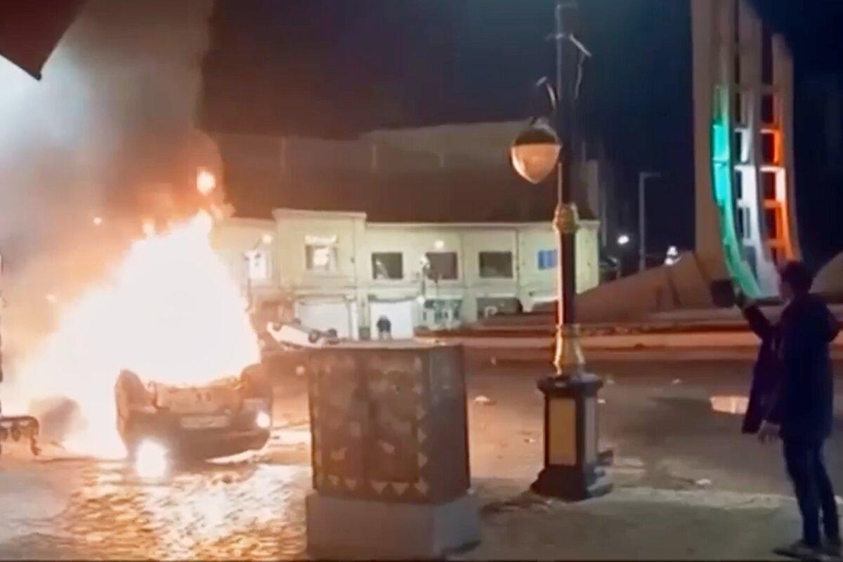 A frame grab from Iranian state television shows a man observing burning vehicles during overnight protests in Zanjan, Iran, on Jan. 9, 2026. (Iranian state TV via AP)