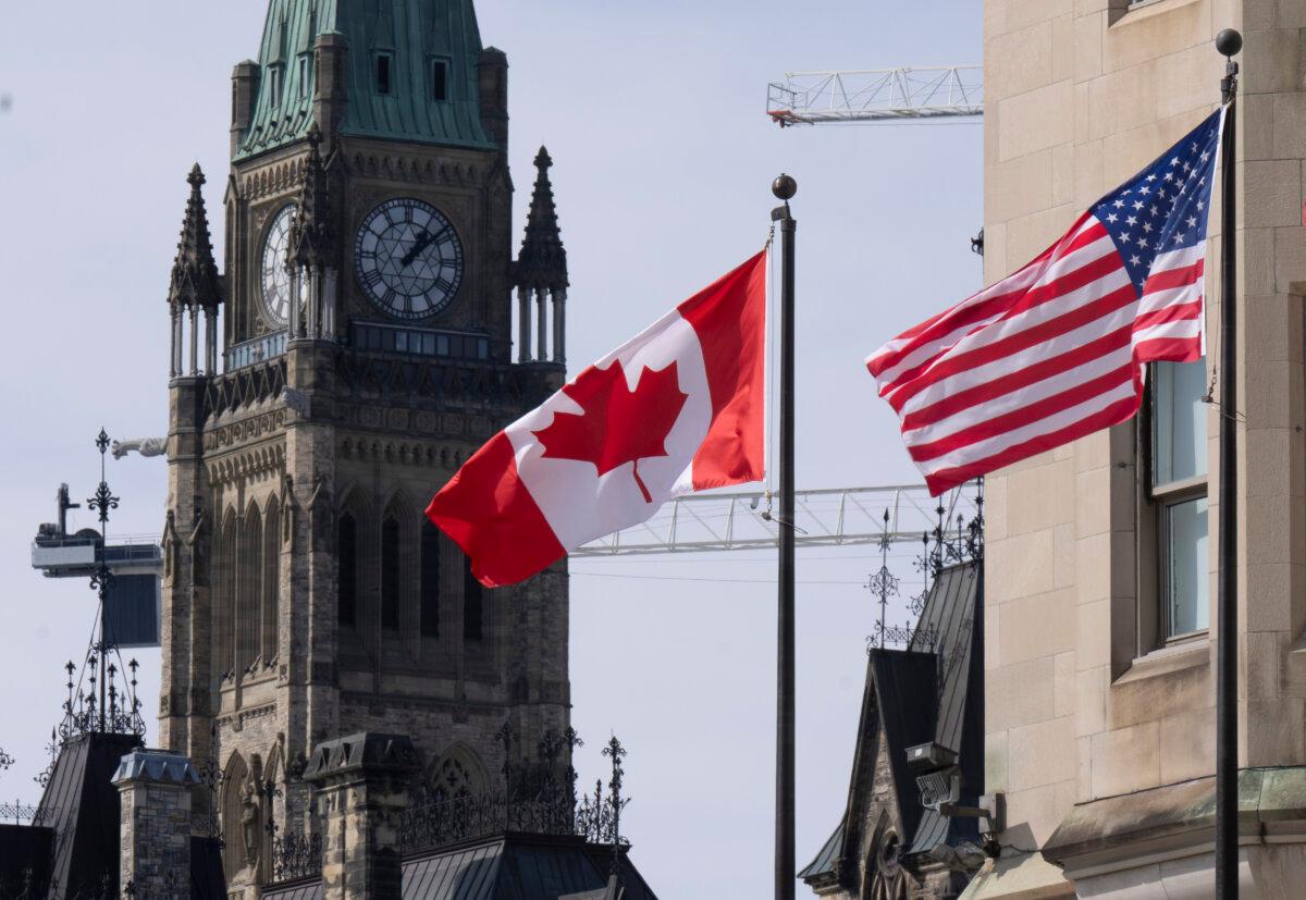 Canadian and U.S. flags are seen flying near Parliament Hill in Ottawa, on March 22, 2023. (The Canadian Press/Adrian Wyld)