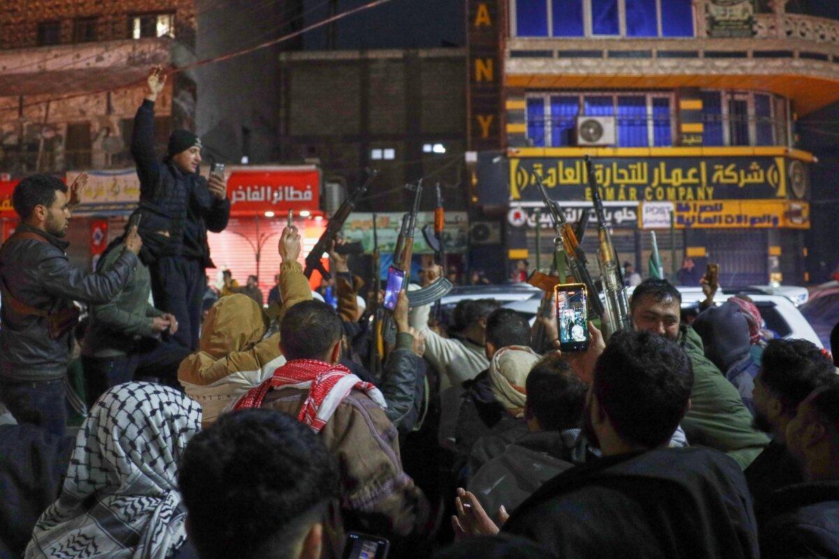 Syrian government troops and local supporters celebrate after taking control of the town from the Syrian Democratic Forces (SDF), in the Al-Naeem roundabout in the city center of Raqqa, northeastern Syria, on Jan. 18, 2026. (Omar Albam/AP Photo)