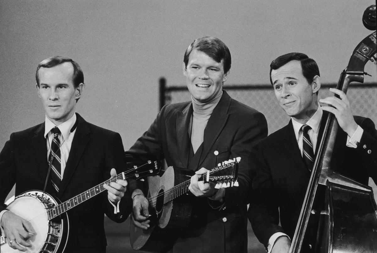 American folk singer Glen Campbell (C) performs on "The Smothers Brothers Comedy Hour" with the American comedy duo, the Smothers Brothers: Tom (L) and Dick, circa 1965. Campbell plays his signature 12-string guitar while Tom plays banjo and Dick plays standup bass. (Hulton Archive/Getty Images)