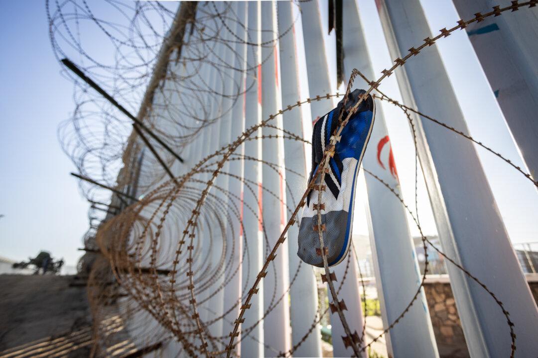A sandal caught in barbed wire sits on the United States border wall outside of San Diego, on Jan. 20, 2026. (John Fredricks/The Epoch Times)