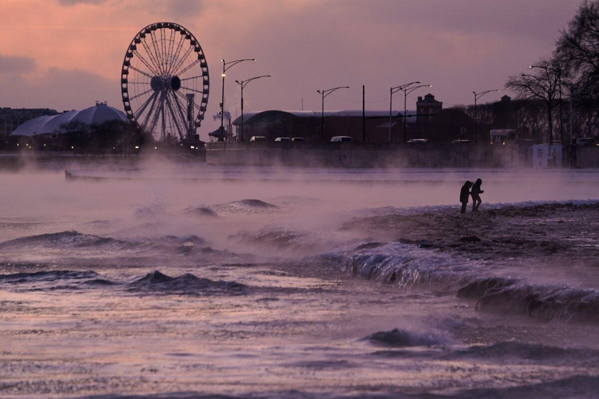 People walk on an ice-covered beach along the shore of Lake Michigan, Friday, Jan. 23, 2026, in Chicago. (AP Photo/Kiichiro Sato)