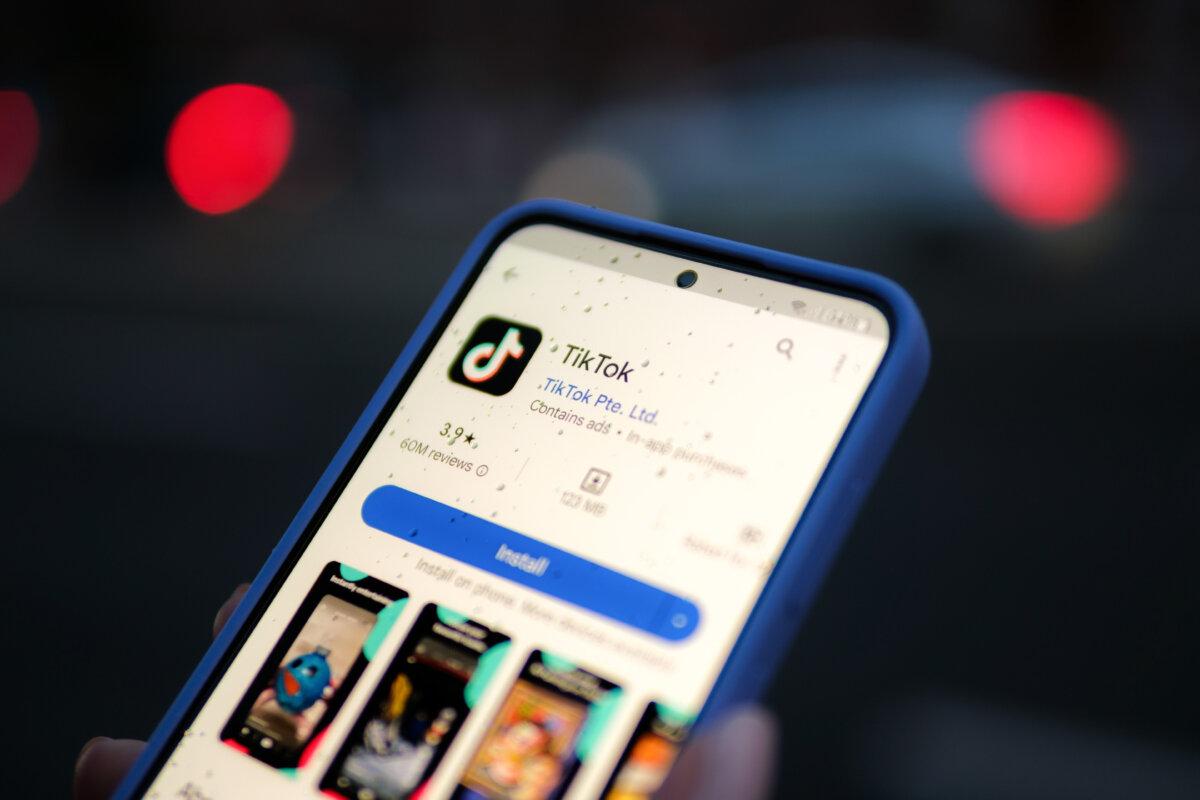 A woman holds a phone displaying the TikTok app on Aug. 11, 2024. (Oleksii Pydsosonnii/The Epoch Times)