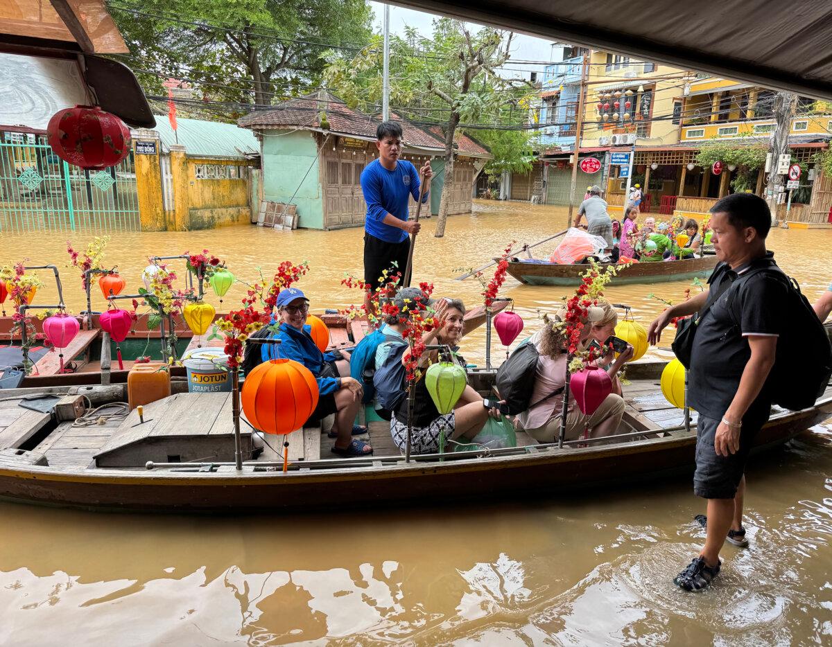 Mr. Nam, right, loads our AdventureWomen group into boats he hired to transport us across the flooded streets of Hoi An. (Lori Rackl/TNS)