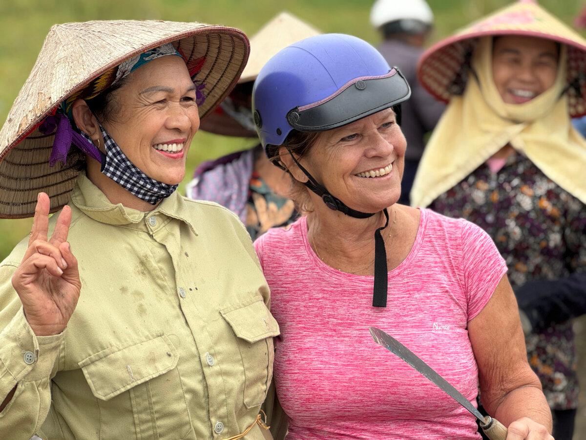 A woman in our group takes a break from the bike to pose for a photo with some workers in the rice paddies. (Lori Rackl/TNS)