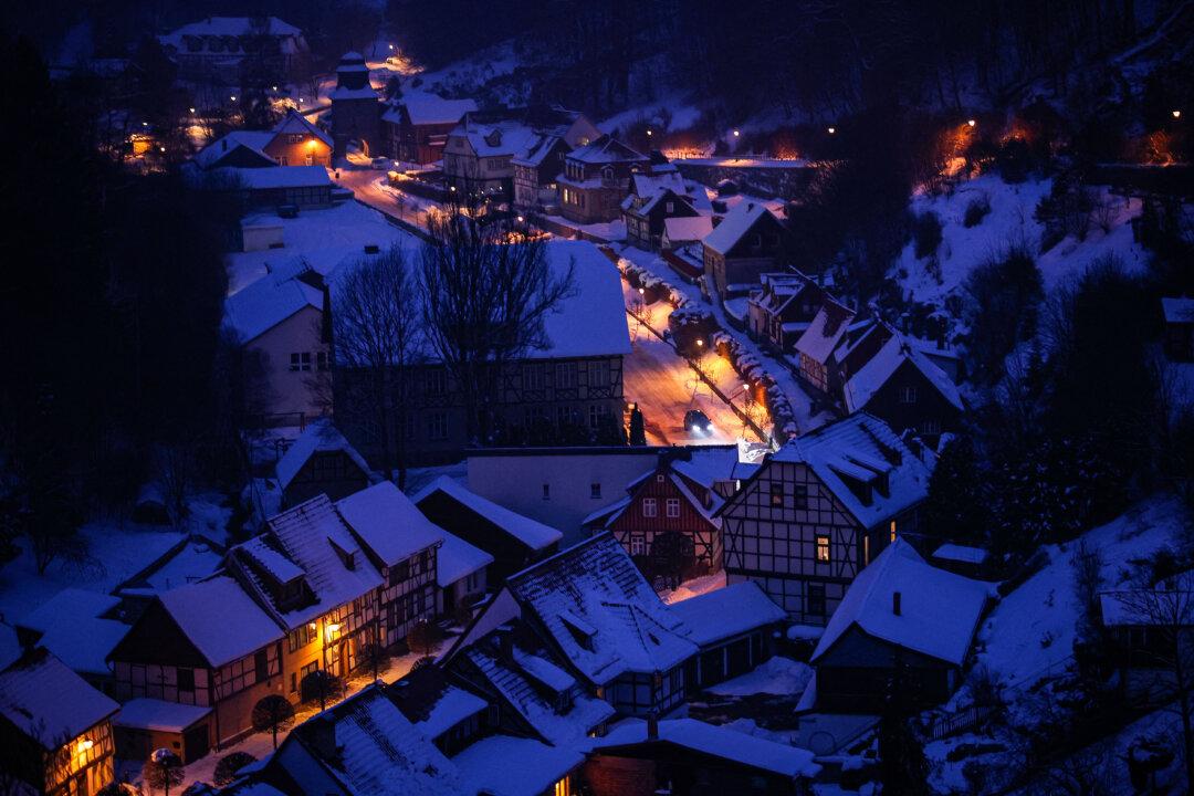 An aerial picture taken on at the fall of the night on February 4, 2026 shows snow lying on the roofs of the half-timbered town of Stolberg, in the southern Harz Mountains, eastern Germany. (Photo by Ronny HARTMANN / AFP via Getty Images)