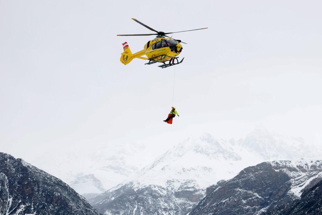 BORMIO, ITALY - FEBRUARY 04: A mountain rescue helicopter flies over mountains as a medic hangs below during the Men's Downhill training on day minus two of the Milano Cortina 2026 Winter Olympics at Stelvio Alpine Skiing Centre on February 04, 2026 in Bormio, Italy. (Photo by Dustin Satloff/Getty Images)