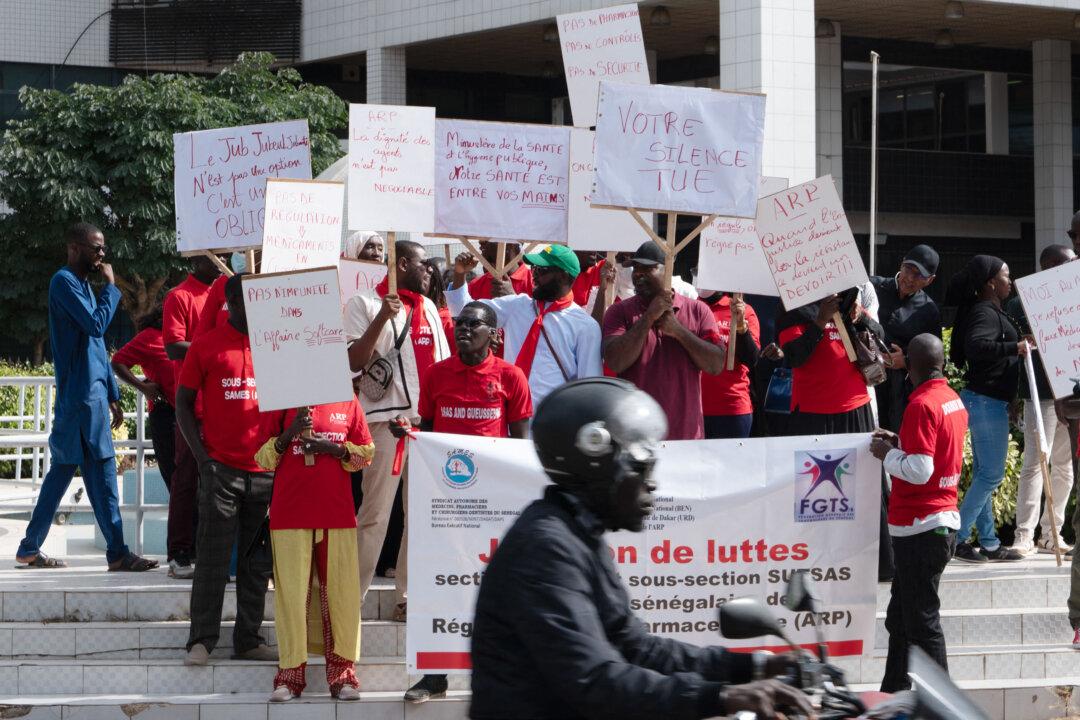 Protesters hold placards as they take part in a demonstration in front of the Ministry of Health to protest the government's silence on the so-called "Softcare Affair" involving Chinese sanitary napkins, in Dakar on February 6, 2026. Anger is mounting in Senegal over the alleged use of expired materials in sanitary pads and diapers by a leading Chinese firm, which denies any wrongdoing or bribery. (Photo by SEYLLOU / AFP via Getty Images)