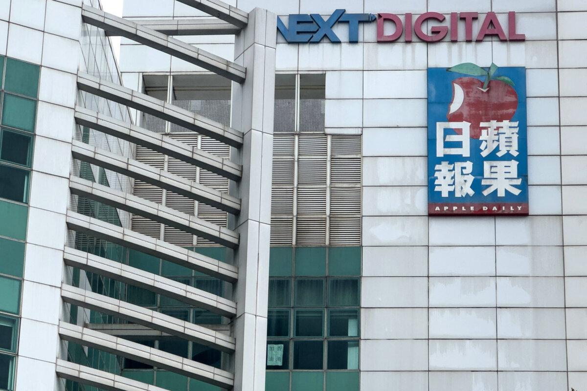 A poster (bottom C), with words reading "Hong Kong add oil," an expression meaning "keep going," is displayed on one of the windows of the shuttered Apple Daily newspaper office in Hong Kong on Feb. 9, 2026. (Yan Zhao/AFP via Getty Images)