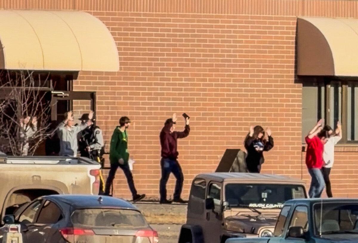 Students walk out of the school building with their hands up after an assailant opened fire at a high school in the town of Tumbler Ridge, B.C., on Feb. 10, 2026. (Western Standard/Jordon Kosik/Handout via Reuters)
