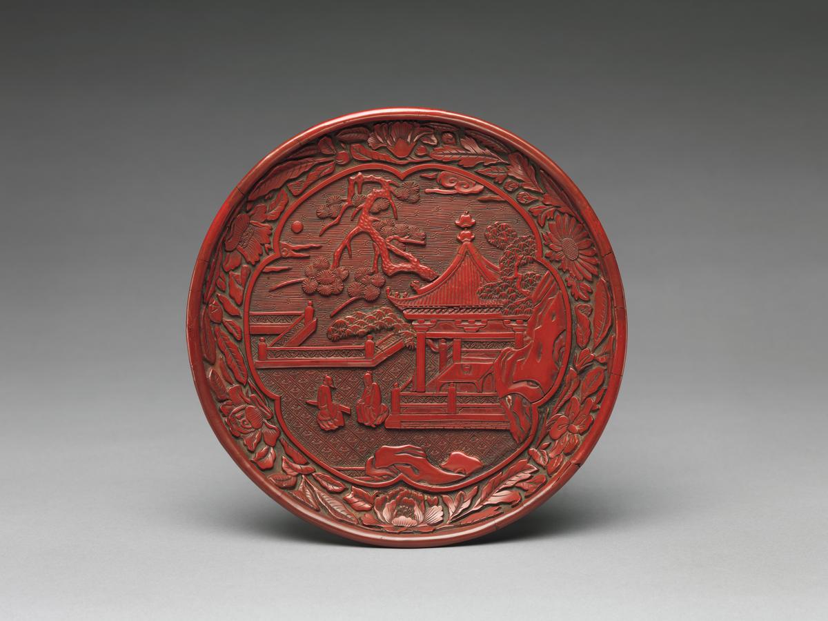 Ming Dynasty dish with garden scene, late 14th century, from China. Carved red lacquer; 1 1/4 inches by 7 3/4 inches. This dish is an example of Chinese red lacquer that was imitated by French craftsman in the 18th century. Metropolitan Museum of Art, New York City. (Public Domain)