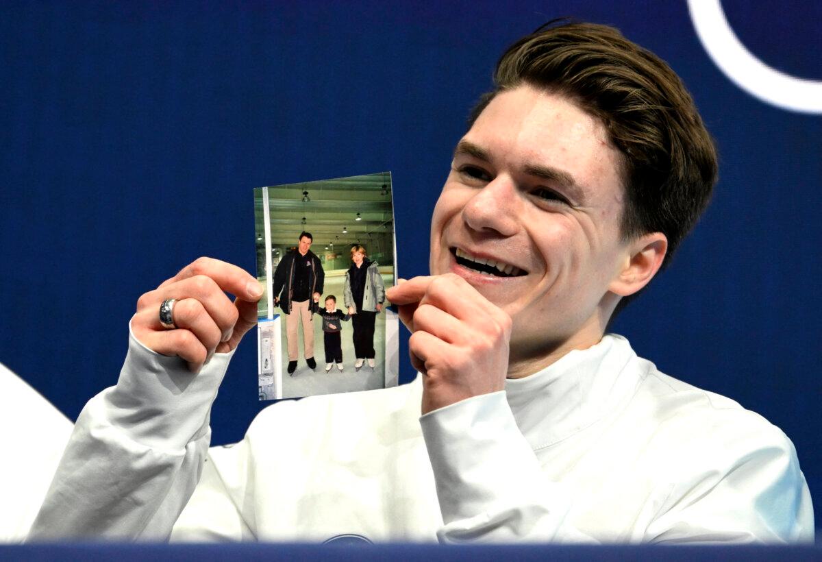 Maxim Naumov of the United States holds a picture of his parents, who died in a plane crash last year, after competing in the figure skating men's singles short program during the Milano Cortina 2026 Winter Olympic Games at Milano Ice Skating Arena in Milan on Feb. 10, 2026. (Wang Zhao/AFP via Getty Images)