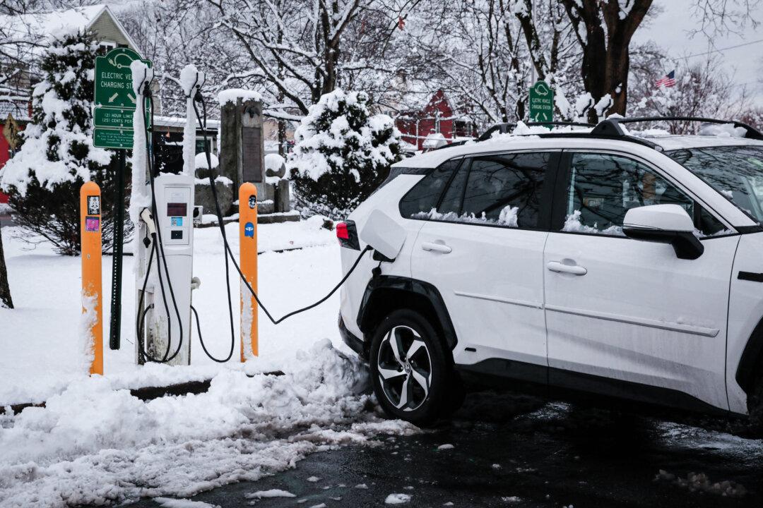 An electric car is charging at a station covered by snow in Sparkill, N.Y., on Feb. 13, 2024. EVs lose 58.8 percent of their value in the first five years after purchase, compared with the industry average for all vehicles of 45.6 percent, according to the automotive research company iSeeCars. (Kena Betancur/AFP via Getty Images)
