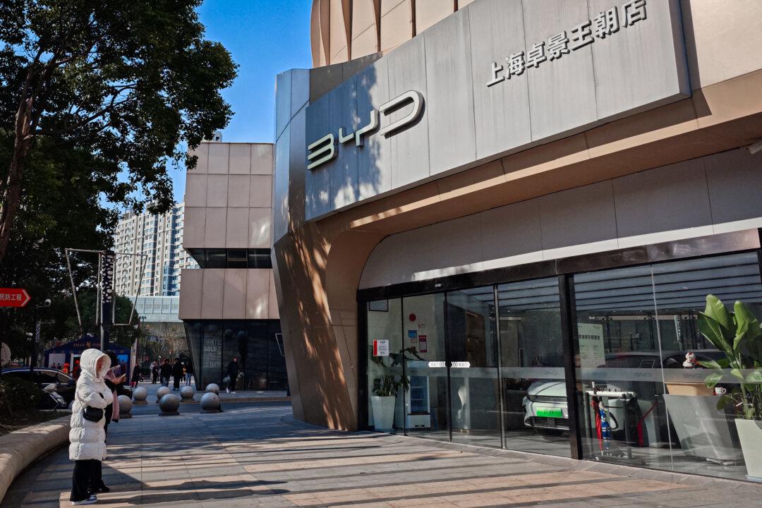People stand outside an auto shop of the Chinese electric vehicle manufacturer BYD Co. Ltd. in Shanghai on Dec. 27, 2024. BYD has displaced Tesla in 2025 as the world’s largest seller by volume, and in some markets, its EVs sell for 30 percent less than other global brands. (STR/AFP via Getty Images)