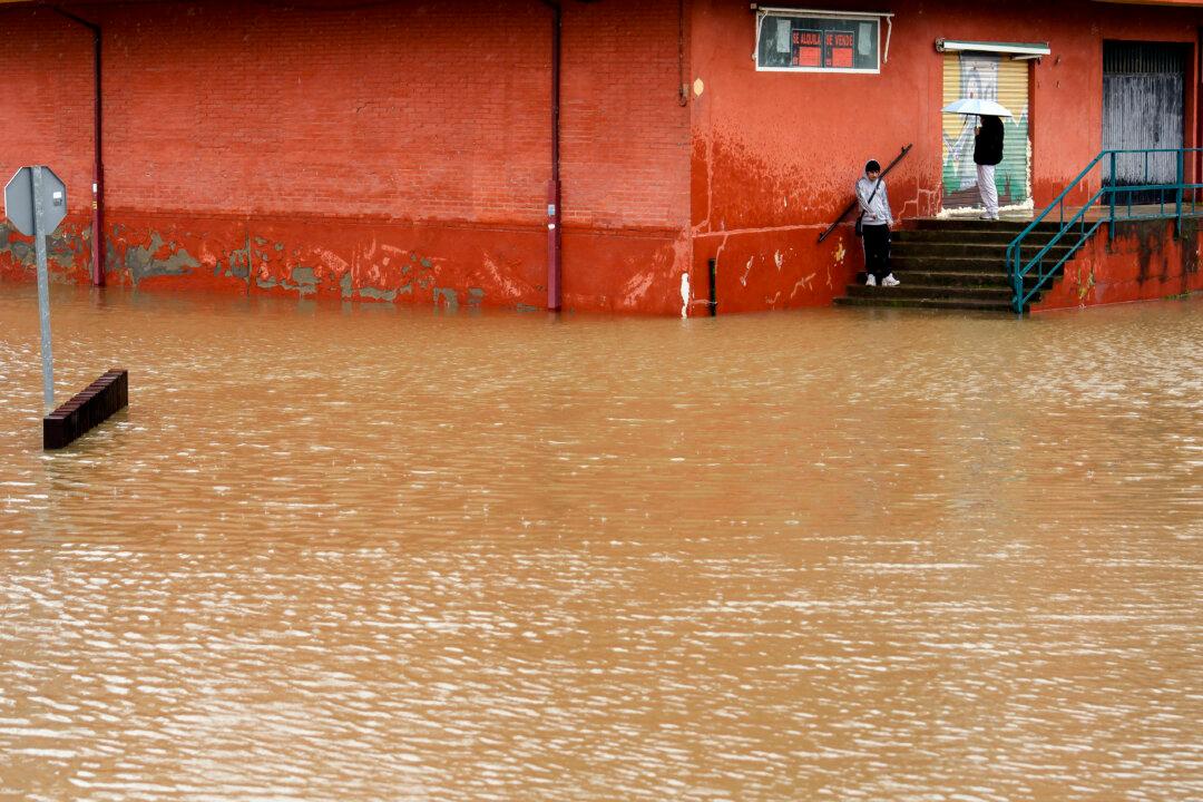 Two people observe floodwaters covering a street of Viana de Cega in the northern Spanish province of Valladolid, after the Cega river burst its banks on February 13, 2026. A 46-year-old woman died after the roof of an industrial warehouse collapsed on her during a severe windstorm that swept across north-eastern Spain, regional authorities said today. The latest storm comes as most of Spain was placed on alert for Storm Oriana, which is sweeping across the country with strong winds, heavy rain, snow in some areas, and rough seas expected. (Photo by CESAR MANSO / AFP via Getty Images)