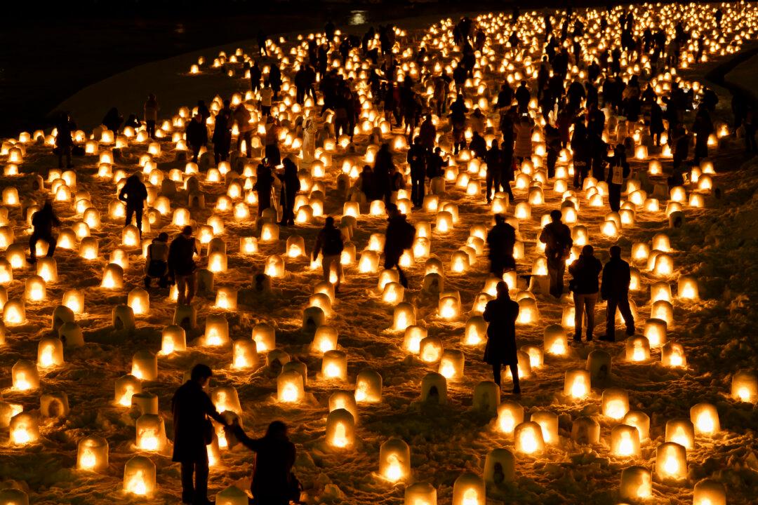 YOKOTE, JAPAN - FEBRUARY 13: People watch candle-flames in snow domes known as kamakura during the Yokote Snow Festival at night on February 13, 2026, in Yokote, Akita Prefecture, Japan. The snow festival is held in one of the heaviest snowfall areas in the country. During the 450-year-old folk festival, altars are built inside snow domes where children play and drink Amazake, a sweet fermented rice drink. (Photo by Tomohiro Ohsumi/Getty Images)