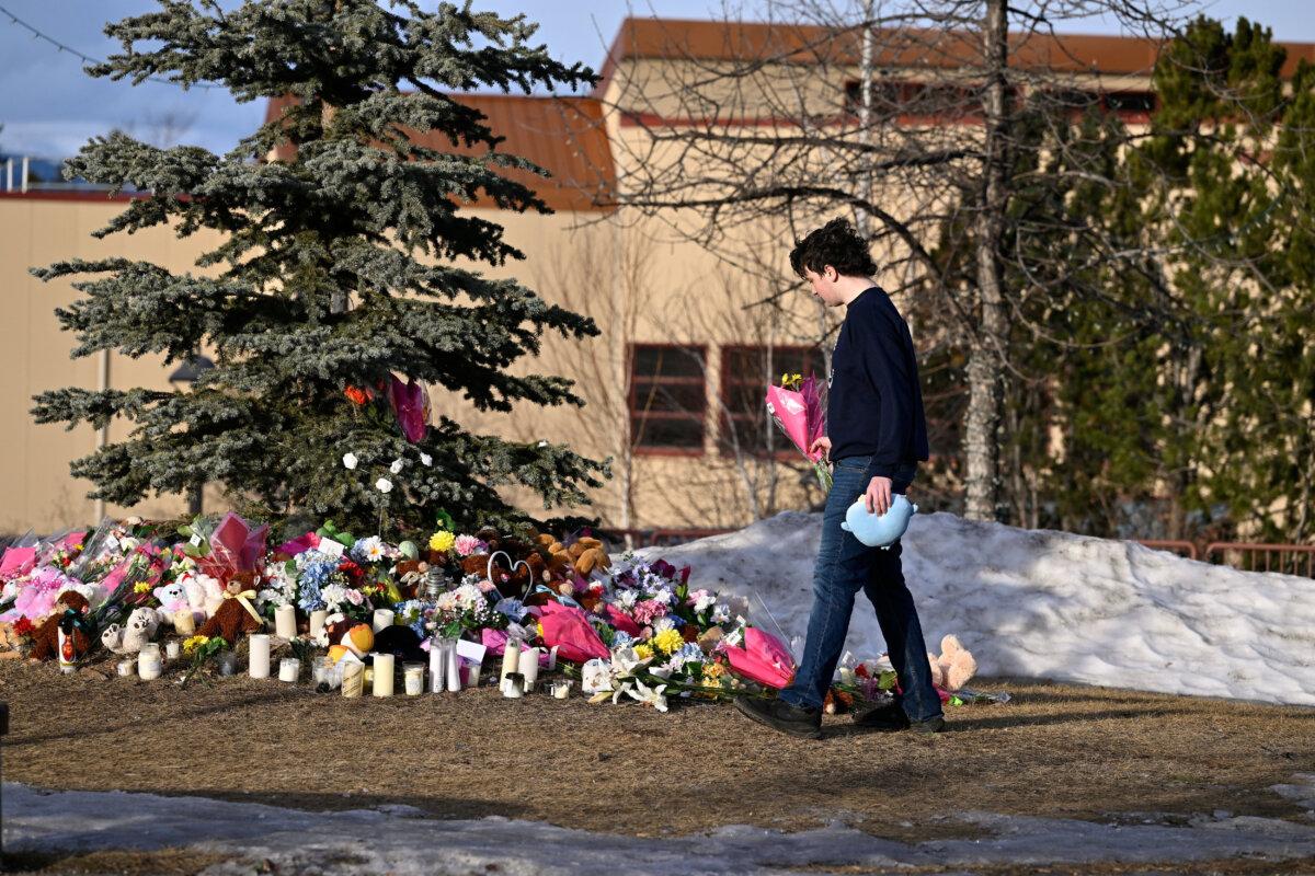 Student Darian Quist takes flowers to a makeshift memorial for the victims two days after a deadly mass shooting took place at a school, in the town of Tumbler Ridge, B.C., on Feb. 12, 2026. (Reuters/Jennifer Gauthier)