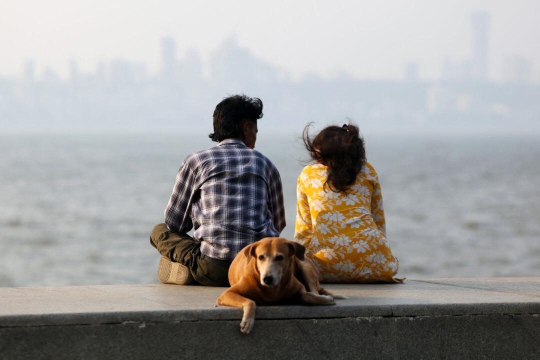 People enjoy the view and ocean breeze at the Marine Drive in Mumbai on February 16, 2026. (Photo by Ludovic MARIN / AFP via Getty Images)