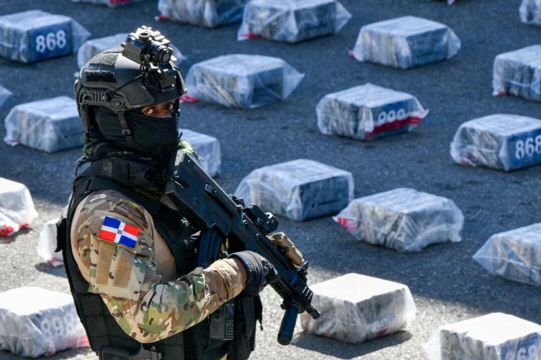 A member of the National Drug Control agency stands guard next to seized packages of cocaine in Santo Domingo on February 16, 2026. The Dominican Republic said it had seized more than two tons of cocaine during a joint operation with the United States, days after the closure of Washington's anti-narcotics office in the Caribbean nation amid corruption suspicions. (Photo by Danny Polanco / AFP via Getty Images)