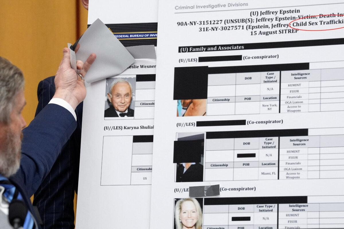Rep. Thomas Massie (R-Ky.) lifts a piece of paper on a board displaying an FBI document, revealing an image of businessman Les Wexner, in Washington on Feb. 11, 2026. (Kent Nishimura/Reuters)