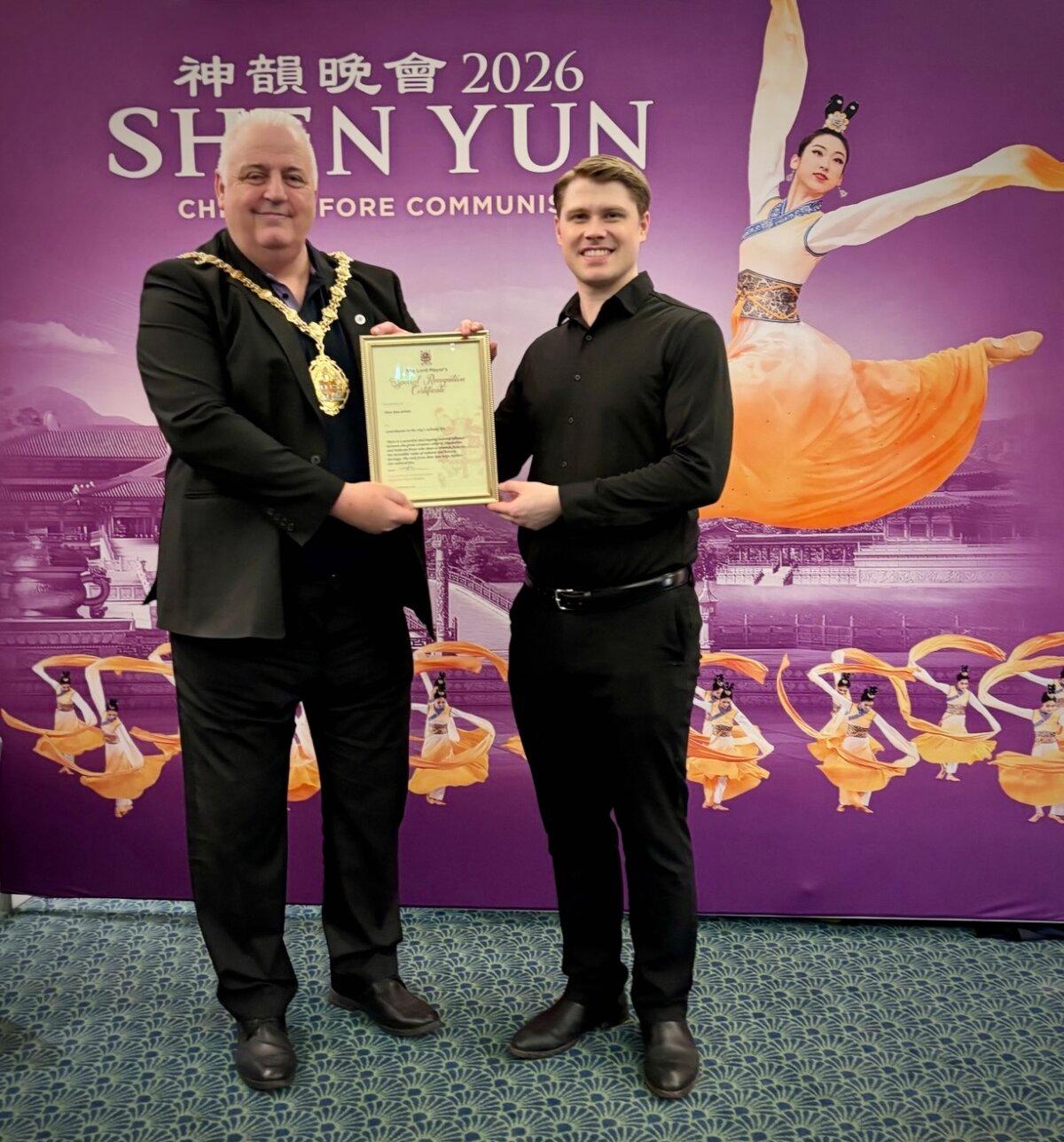 Steve Watkins (L) presents a Certificate of Recognition to Shen Yun's male emcee at the Regent Theatre on Feb. 18, 2026. (Fei Chen/The Epoch Times)