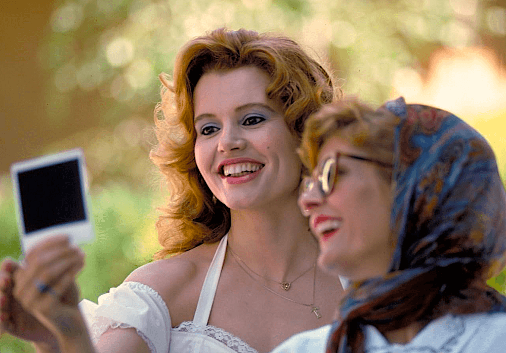 Thelma (Geena Davis, L) and Louise (Susan Sarandon) take a Polaroid selfie, in “Thelma & Louise.” (MGM)