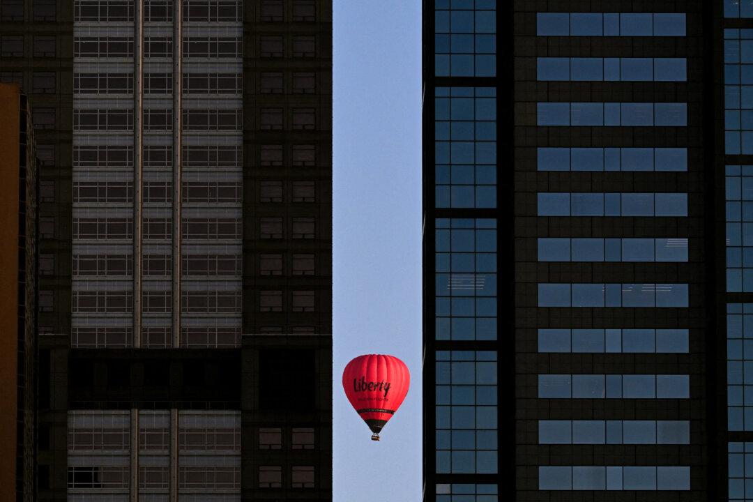 TOPSHOT - A hot-air balloon carrying tourists passes by the Melbourne central business district skyline during an early morning flight on February 23, 2026. (Photo by William WEST / AFP via Getty Images)