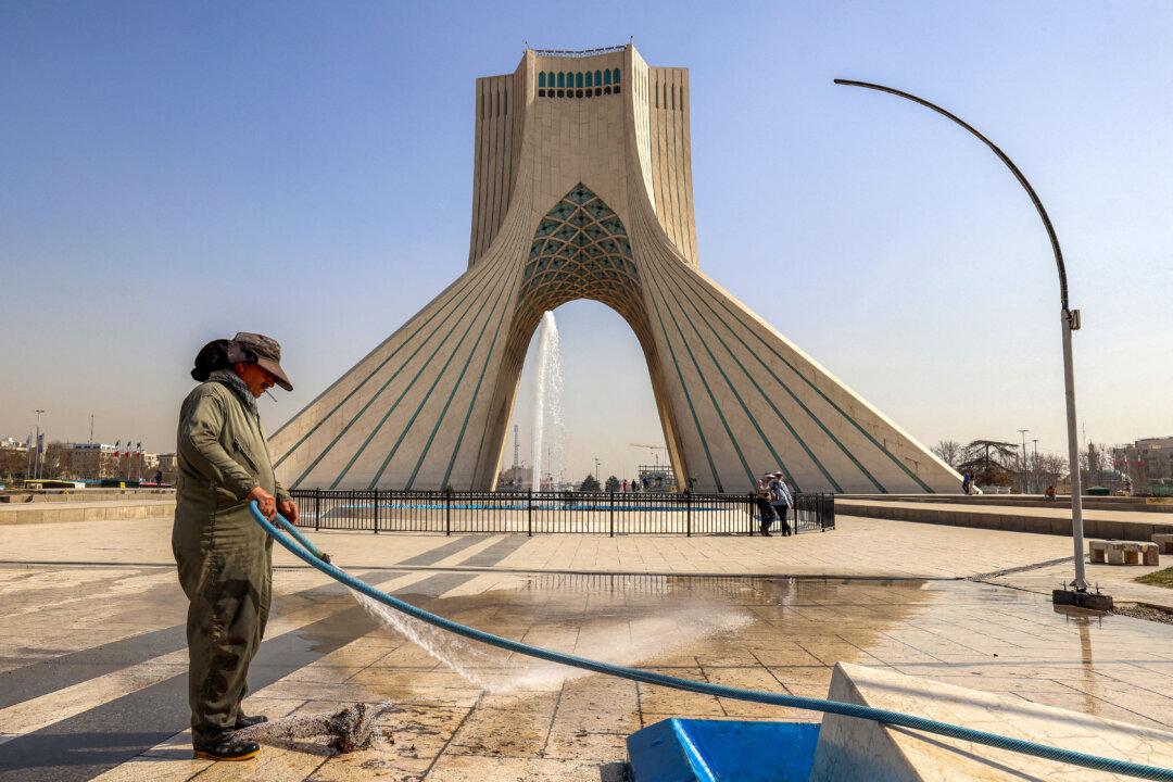 A municipal worker uses a hose to clean an area of Azadi (Freedom) Square near the landmark Azadi Tower in Tehran on February 23, 2026. The 45-metre-tall marble-clad Azadi Tower, formerly known as Shahyad Tower (Shah's Memorial Tower'), was commissioned by Mohammad Reza Pahlavi, the last Shah of Iran, to mark the 2,500-year celebration of the Persian Empire, and completed in 1971. It was erected at the westernmost entrance to the city of Tehran. (Photo by ATTA KENARE / AFP via Getty Images)