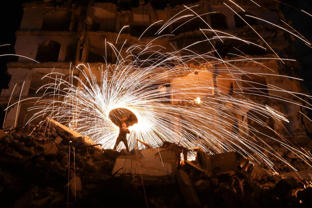 TOPSHOT - A Displaced Palestinian plays with fireworks after breaking his fast, outside a damaged building at the Jabalia refugee camp in the northern Gaza Strip, during the Muslim holy fasting month of Ramadan, on February 23, 2026. (Photo by Omar AL-QATTAA / AFP via Getty Images)