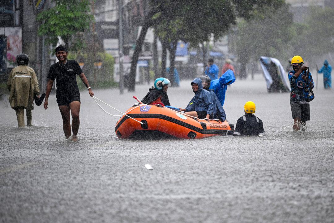 Local residents move hotel guests using a rubber boat through the water on an inundated street amid floods following heavy rain at Legian Kuta near Denpasar on Indonesia's resort island of Bali on February 24, 2026. (Photo by SONNY TUMBELAKA / AFP via Getty Images)